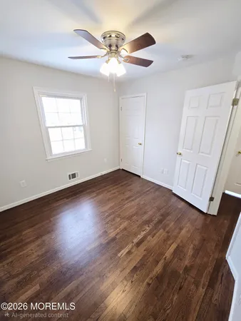 an empty room with wooden floor chandelier fan and windows