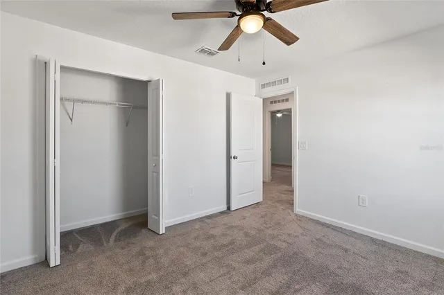 an empty room with closet and a chandelier fan