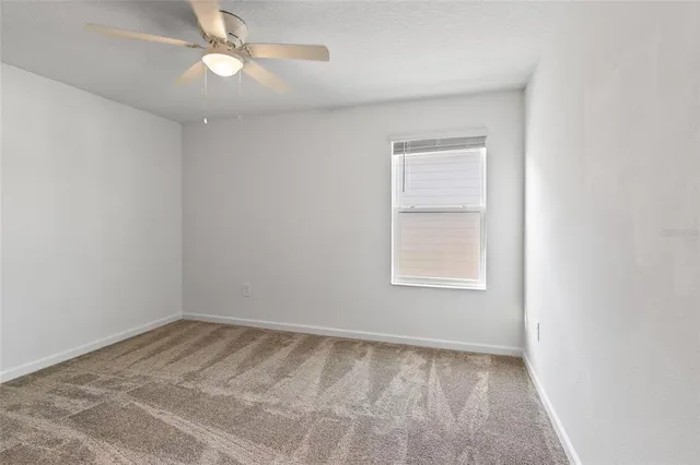 an empty room with a window and a fan