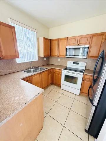 a kitchen with a sink a stove top oven and cabinetry