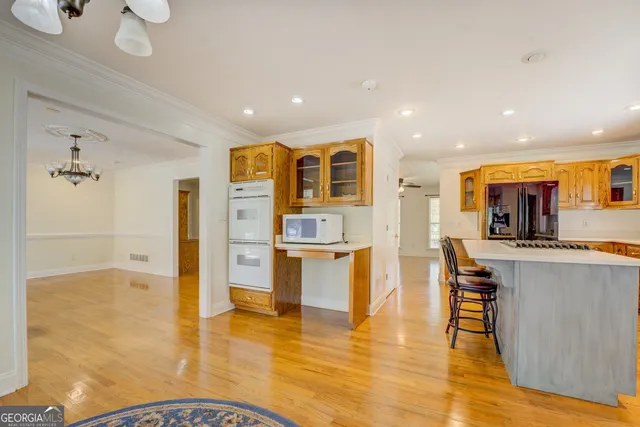 a view of an empty room with wooden floor and a ceiling fan