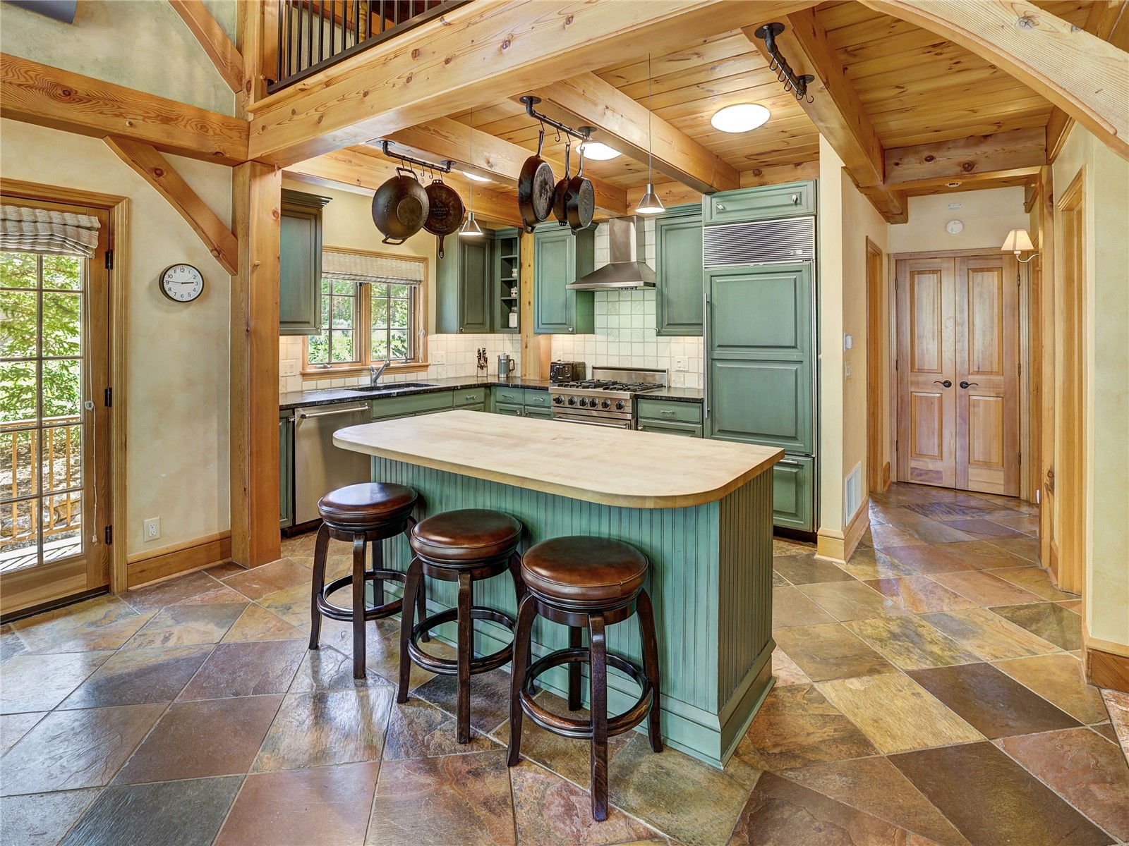 840 Penstemon Road Keystone, CO 80435 - Photo 11 of 50 Kitchen with green cabinets, high end appliances, wall chimney exhaust hood, stone tile flooring, and butcher block counters