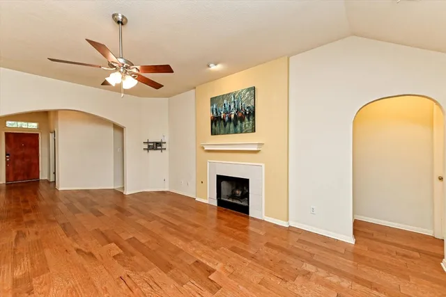 a view of a livingroom with a fireplace a ceiling fan and wooden floor