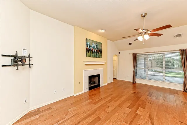a view of a livingroom with a fireplace a ceiling fan and wooden floor