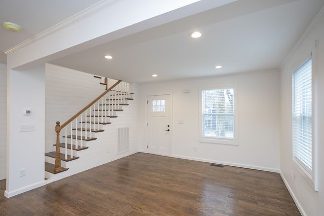a view of an empty room with wooden floor and windows