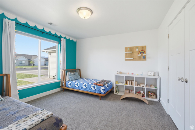 1422 West 3410th Street South Logan, UT 84321 - Photo 21 of 33 Spacious room featuring a large window, neutral carpeting, a built-in closet with panel doors, and a ceiling-mounted light fixture