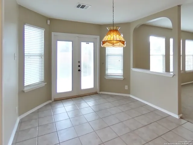 a view of an empty room with window and chandelier fan