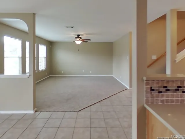 an empty room with windows and ceiling fan