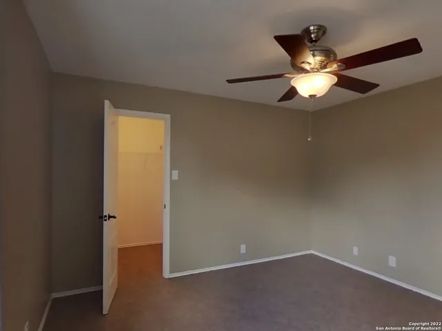 an empty room with closet and a chandelier fan
