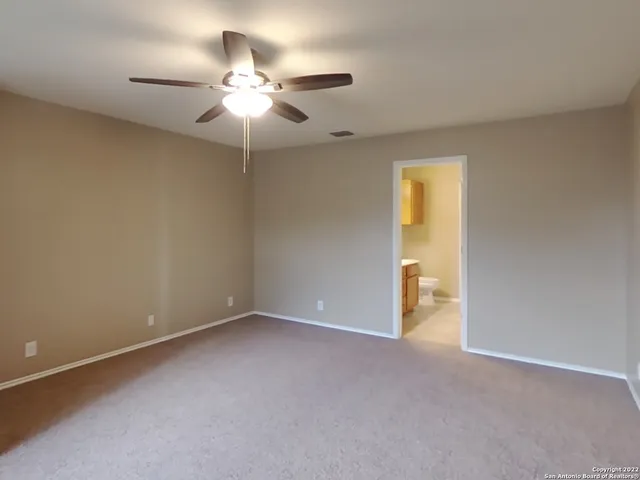 a view of an empty room with a chandelier fan