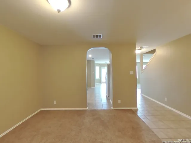 an empty room with chandelier fan and windows