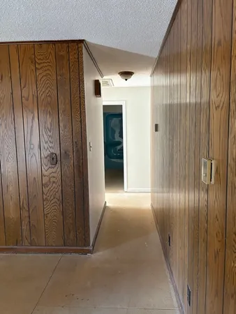 a view of a hallway with wooden floor and a bathroom