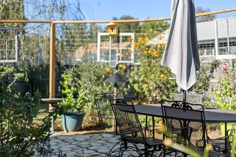 a balcony with table and chairs and potted plants