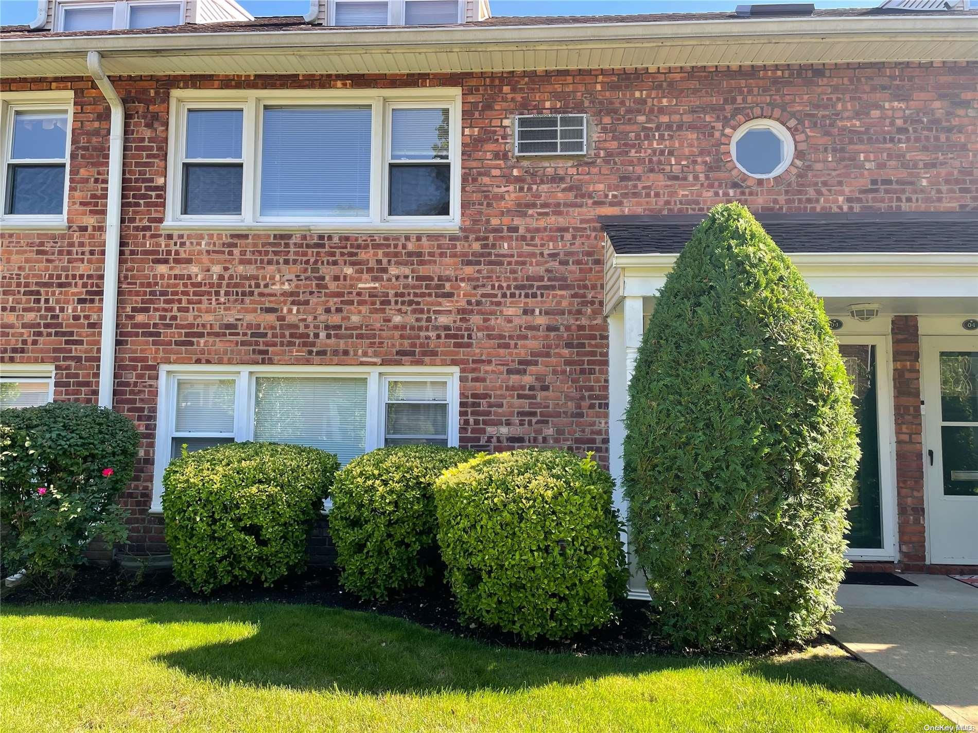 a view of a brick house with a yard and plants