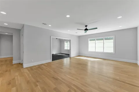 a view of empty room with wooden floor and fan