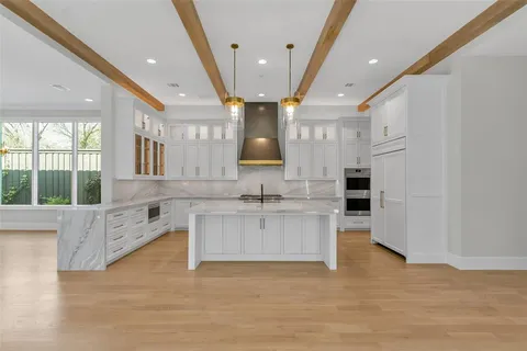 a large kitchen with stainless steel appliances kitchen island granite countertop a stove and a large window