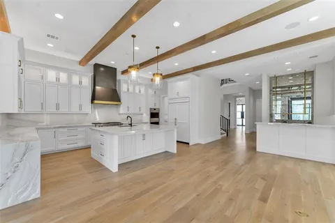 a large white kitchen with lots of counter space a sink and stainless steel appliances