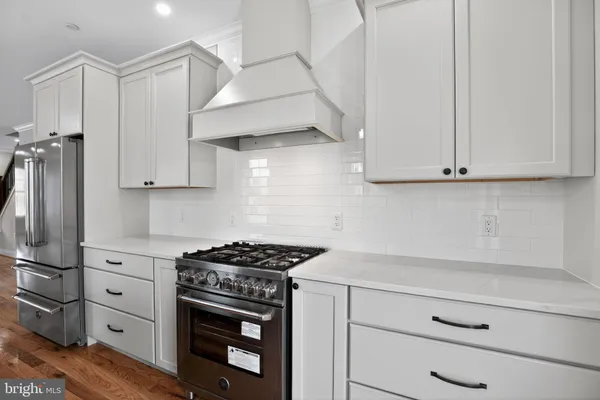 a kitchen with stainless steel appliances granite countertop white cabinets and a stove top oven