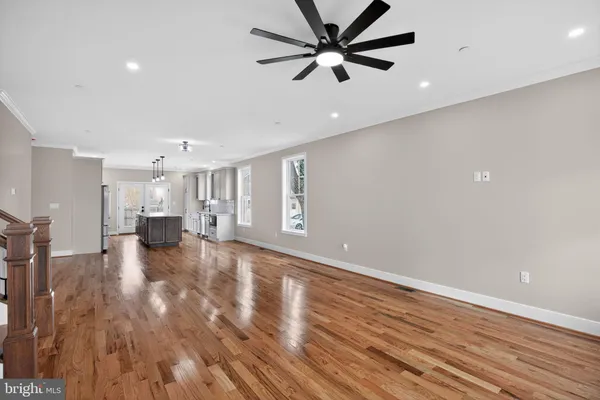 a view of an empty room with wooden floor and a ceiling fan