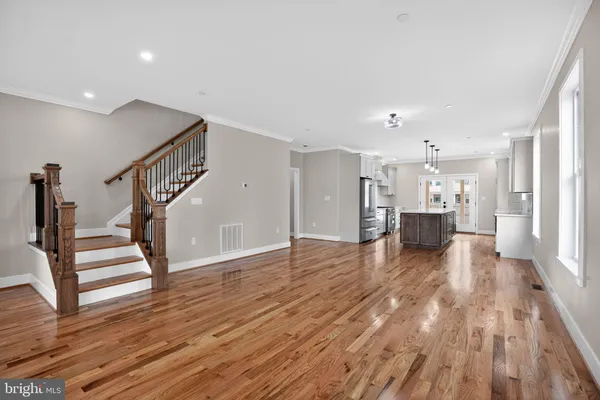 a view of empty room with wooden floor and kitchen