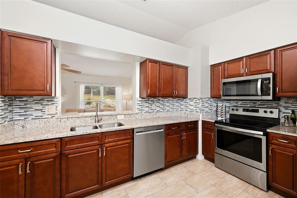 10618 Lake Ralph Drive Clermont, FL 34711 - Photo 10 of 26 a kitchen with stainless steel appliances granite countertop a sink stove and microwave