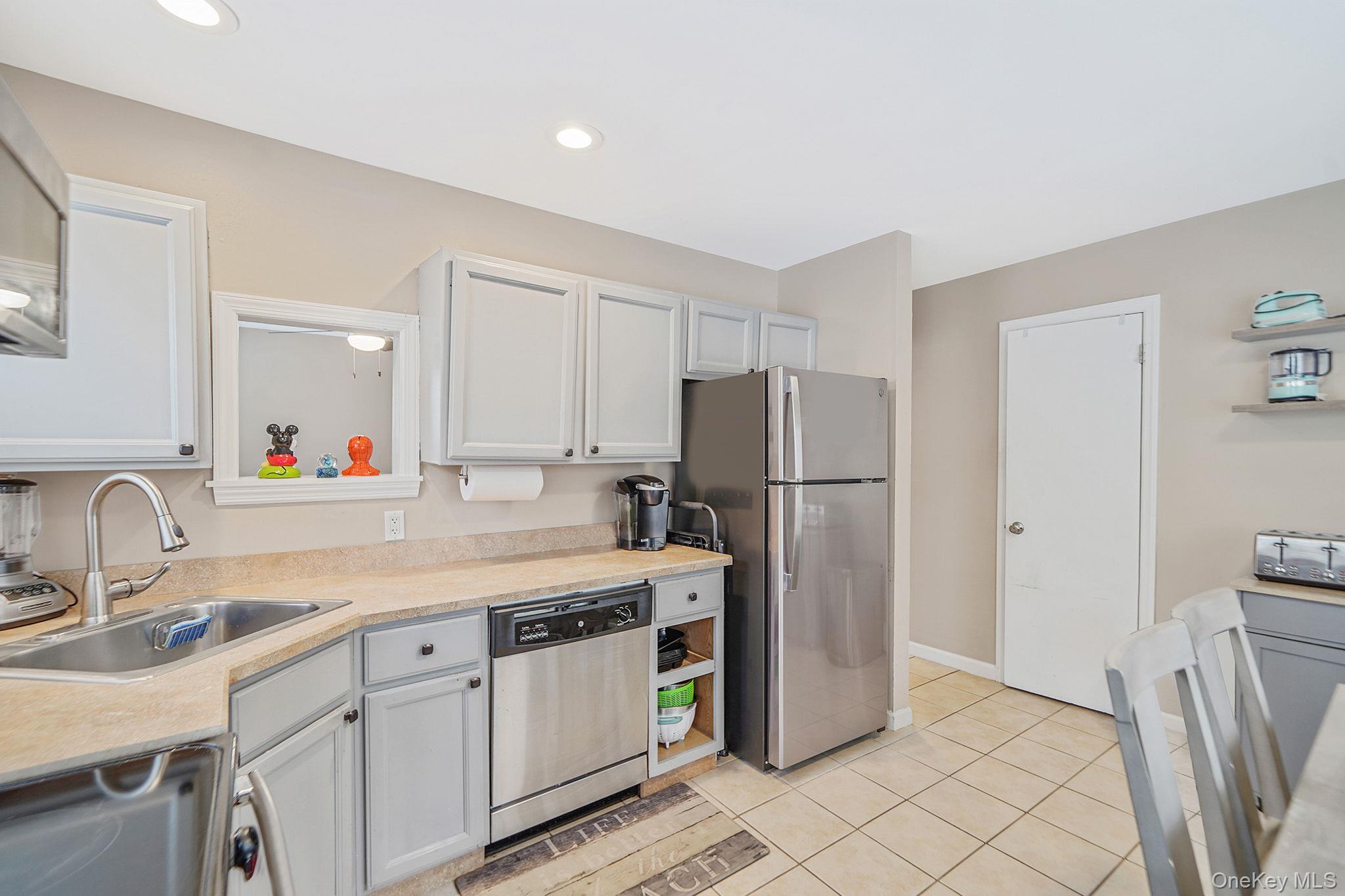4 Willow Road Rocky Point, NY 11778 - Photo 11 of 30 Kitchen featuring light countertops, appliances with stainless steel finishes, light tile patterned floors, white cabinetry, and recessed lighting