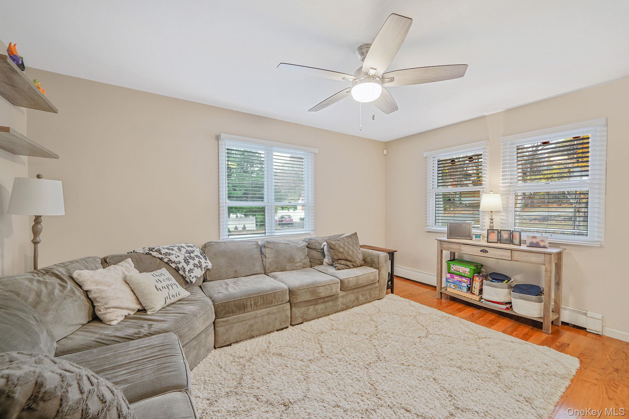 4 Willow Road Rocky Point, NY 11778 - Photo 8 of 30 Living room featuring light wood finished floors, a baseboard radiator, a baseboard heating unit, and a ceiling fan