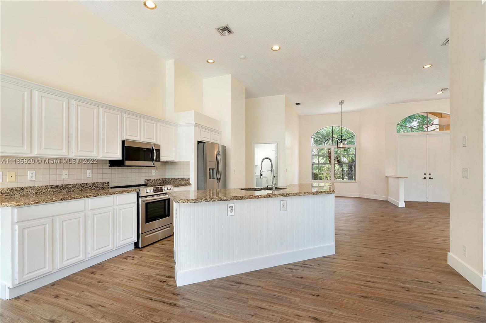 2660 Palmer Place Weston, FL 33332 - Photo 8 of 22 a large kitchen with granite countertop a stove top oven a sink a counter space and wooden floor