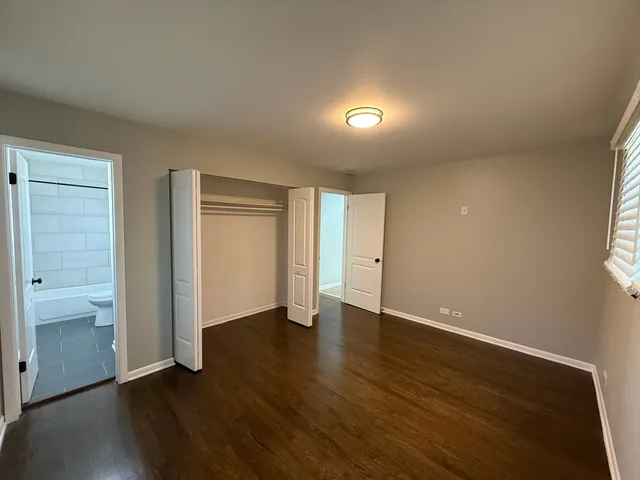 an empty room with wooden floor & closet area