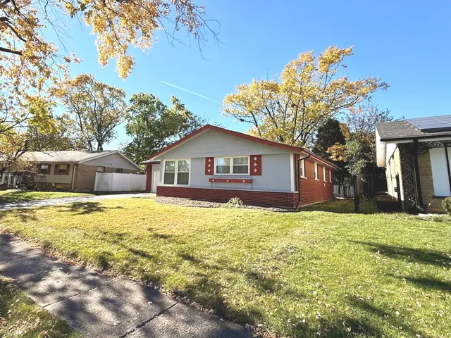 a front view of house with yard and trees in the background
