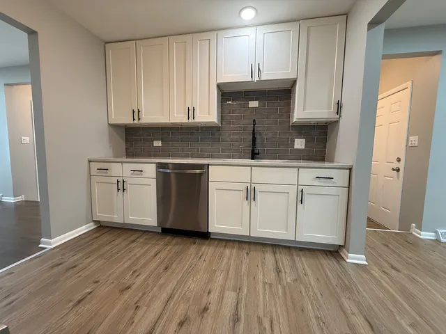 a kitchen with stainless steel appliances a white cabinets and wooden floor