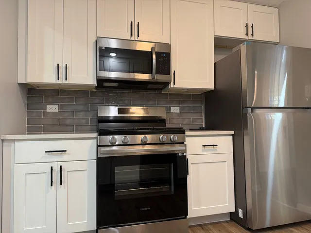 a kitchen with stainless steel appliances white cabinets white stove and a refrigerator