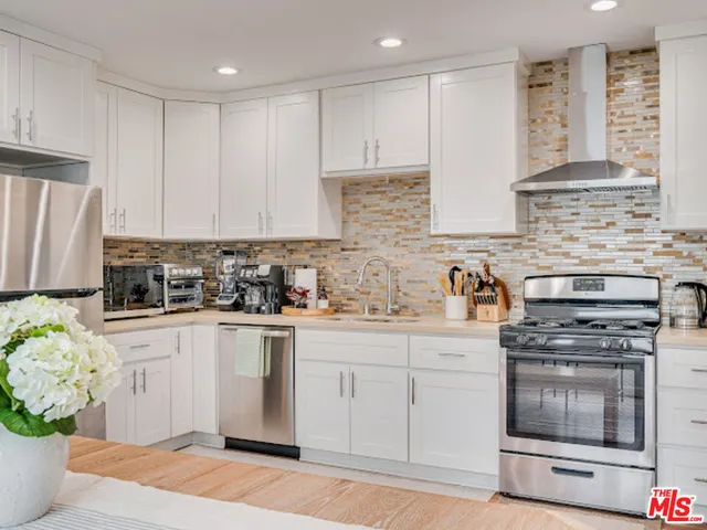 a kitchen with stainless steel appliances granite countertop a stove a sink and a refrigerator