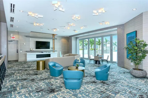 a living room with furniture a flat screen tv and kitchen view
