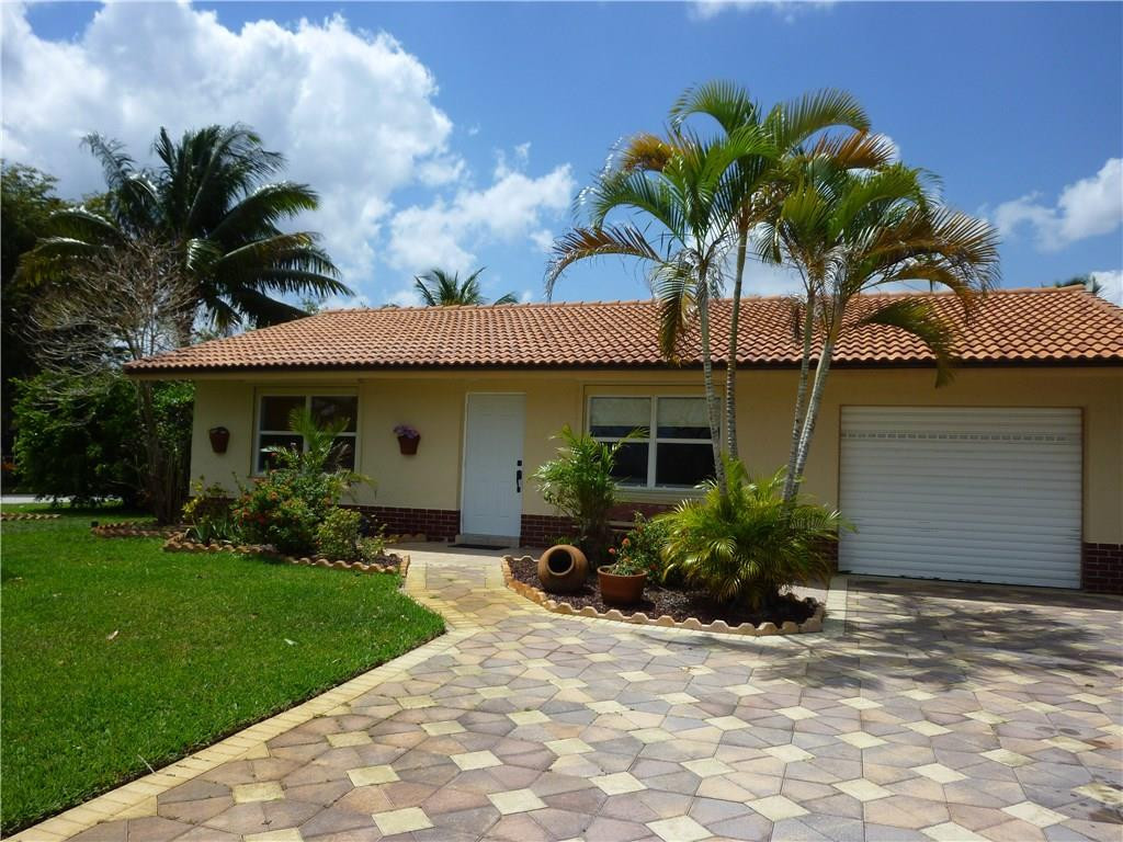 7305 Northwest 95th Way Tamarac, FL 33321 - Photo 2 of 14 a front view of a house with a yard and potted plants