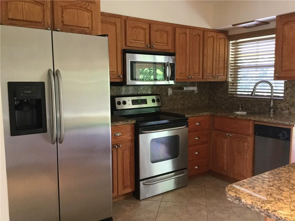 7305 Northwest 95th Way Tamarac, FL 33321 - Photo 3 of 14 a kitchen with stainless steel appliances granite countertop a refrigerator a stove and a sink with wooden floor