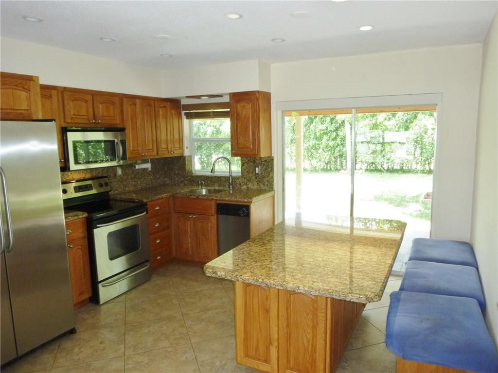 7305 Northwest 95th Way Tamarac, FL 33321 - Photo 4 of 14 a kitchen with stainless steel appliances granite countertop a stove a sink and a refrigerator