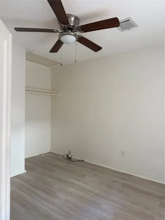 an empty room with a ceiling fan and wooden floor