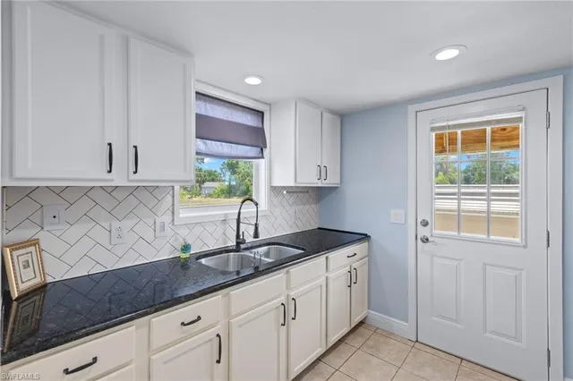 a kitchen with stainless steel appliances granite countertop white cabinets sink and window