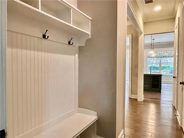 a view of a hallway with wooden floor and a kitchen space