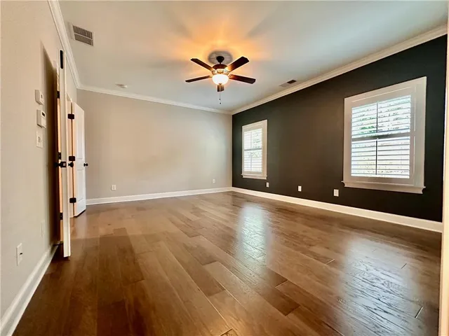 a view of an empty room with window and wooden floor