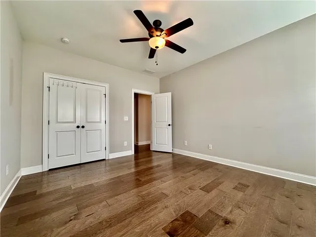 an empty room with wooden floor and ceiling fan