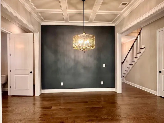 a view of an empty room with stairs and wooden floor