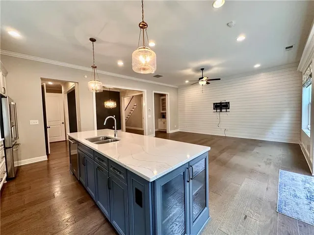 a large kitchen with kitchen island a sink a stove and a wooden floor