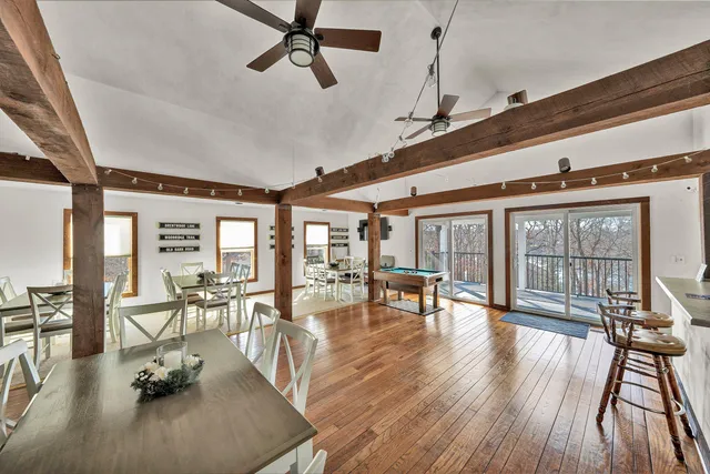 a dining room with wooden floor a chandelier a glass table and chairs