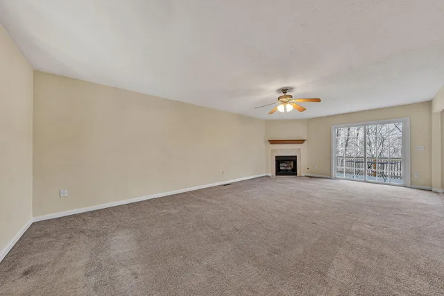 a view of an empty room with a window and fireplace