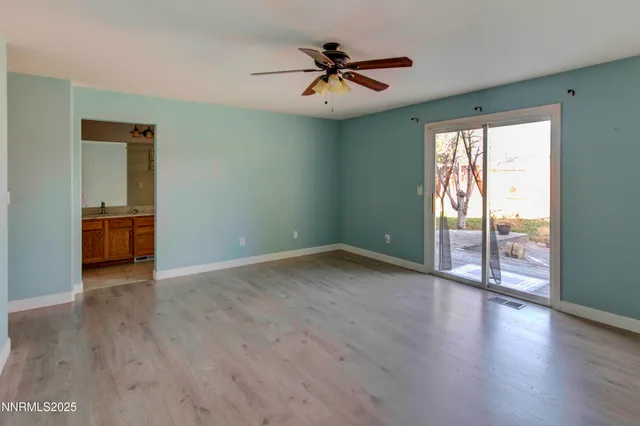 an empty room with wooden floor fan and windows