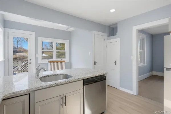 a kitchen with granite countertop a sink and a white wooden cabinets