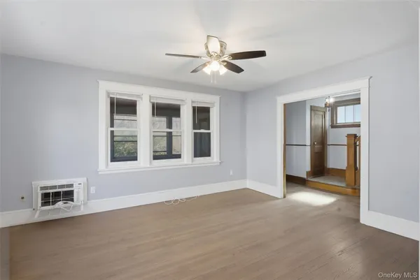 a view of an empty room with a window and kitchen view
