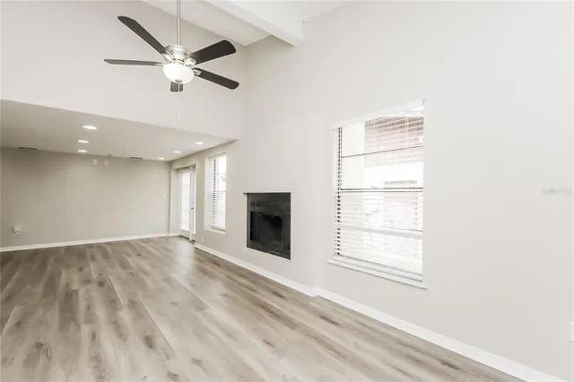an empty room with windows and ceiling fan